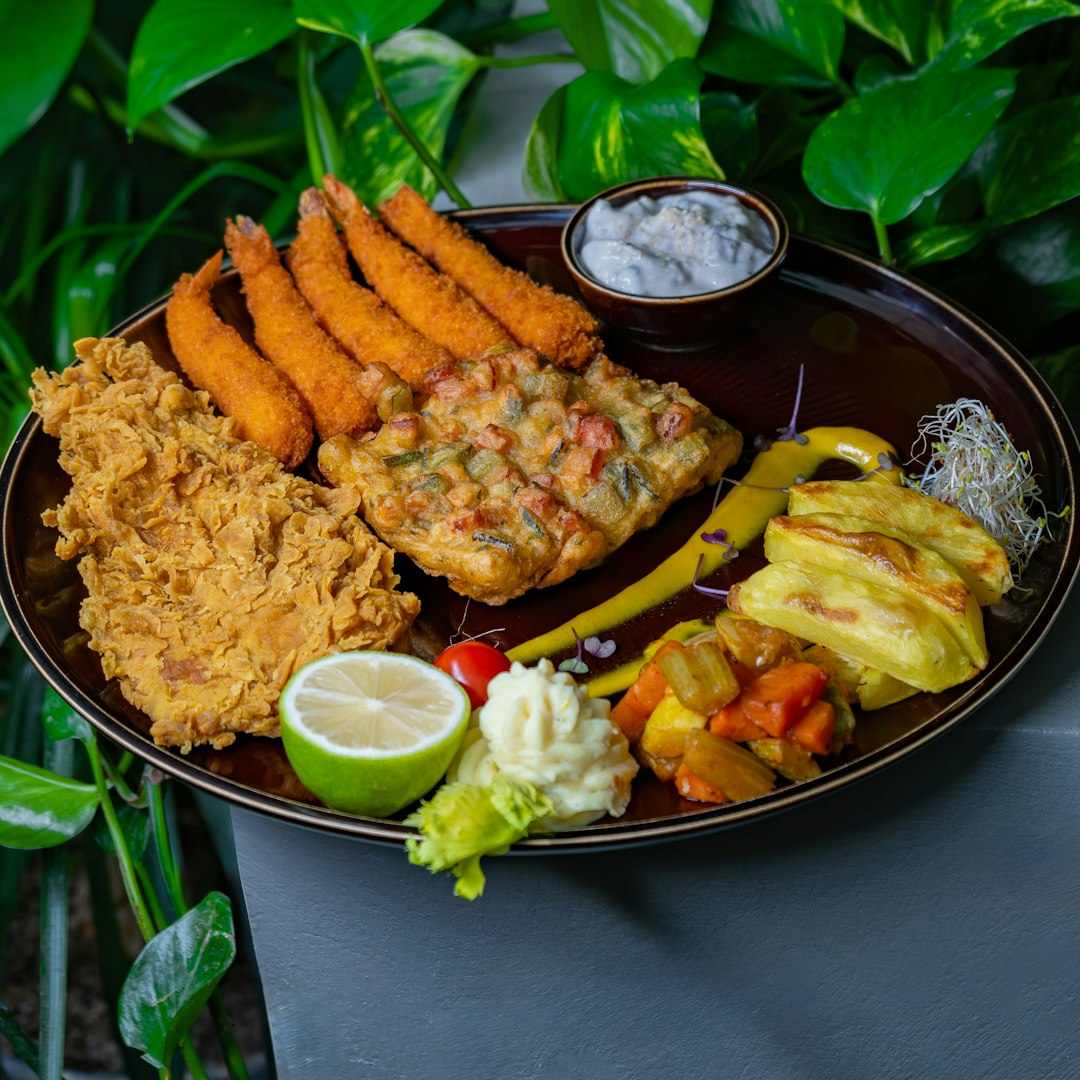 A plate of fried food with a side of fruit and vegetables