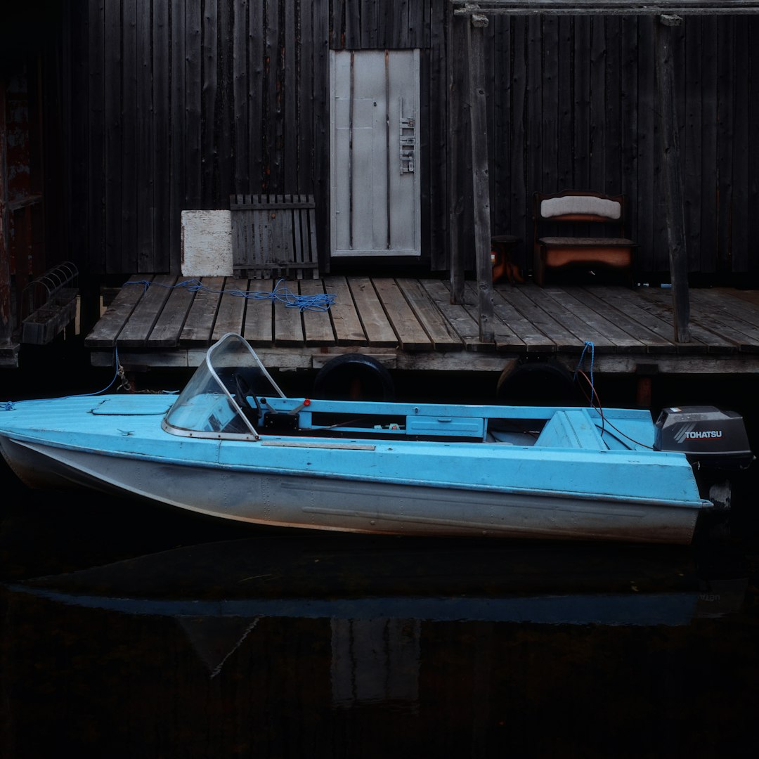 A blue motorboat rests by a weathered wooden dock