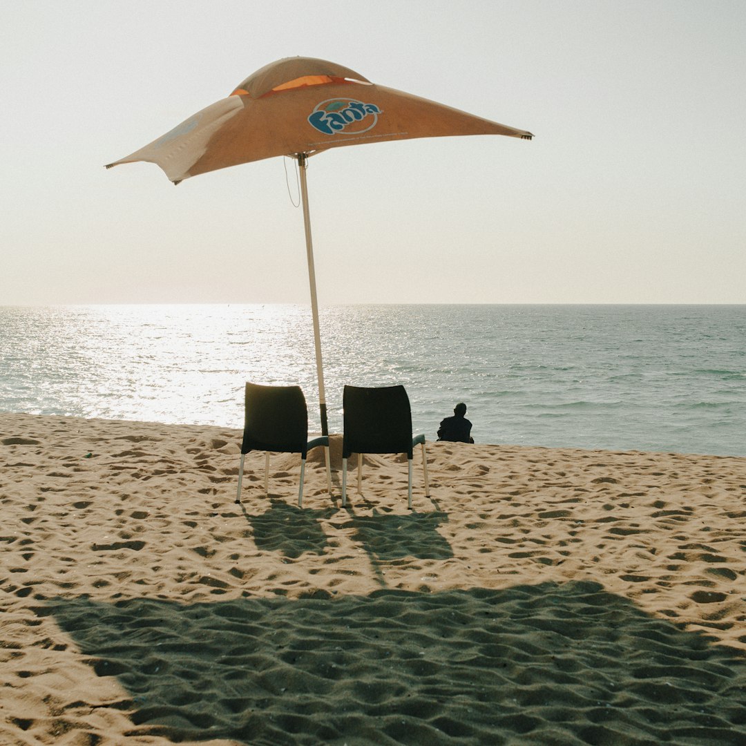 Two chairs under an umbrella on a sandy beach