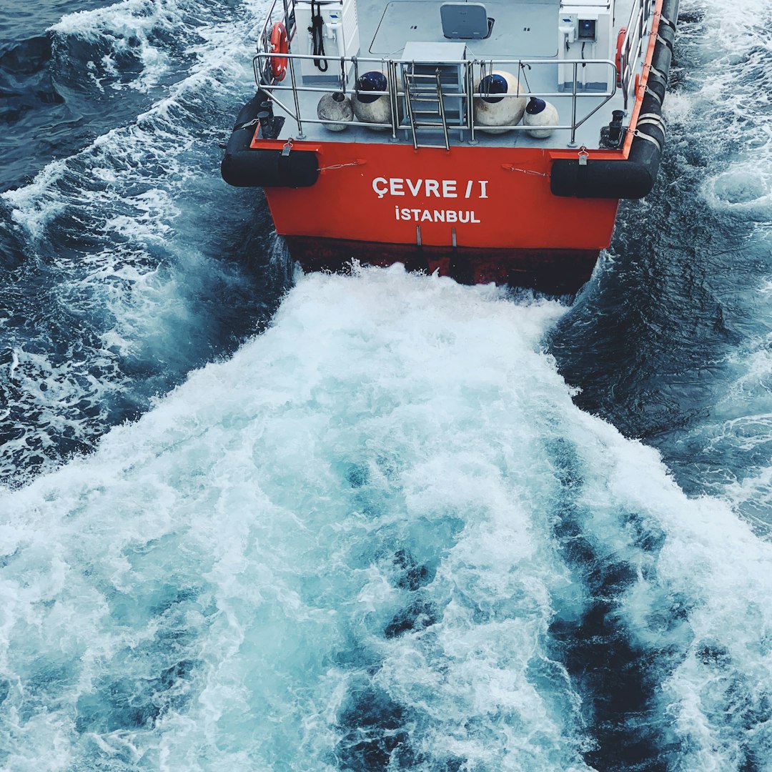 a red and white boat in rough water
