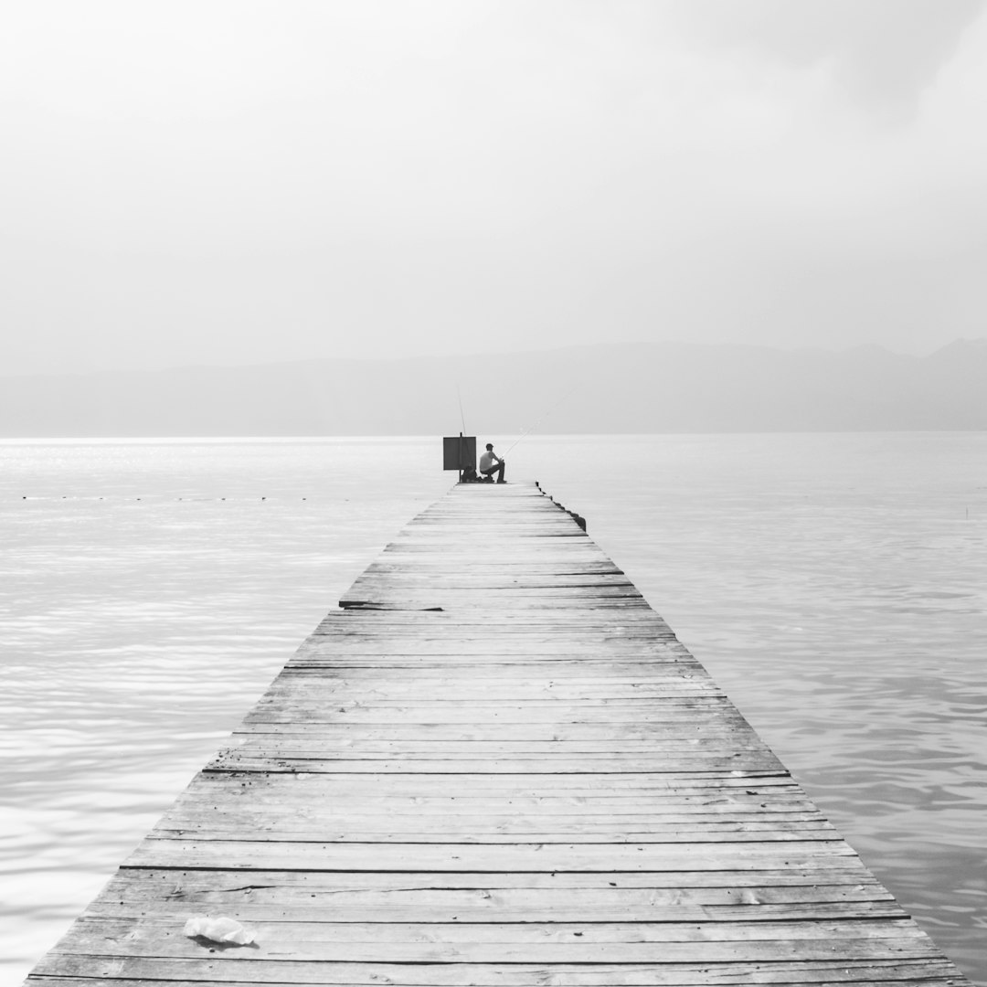 grayscale photo of wooden dock on sea