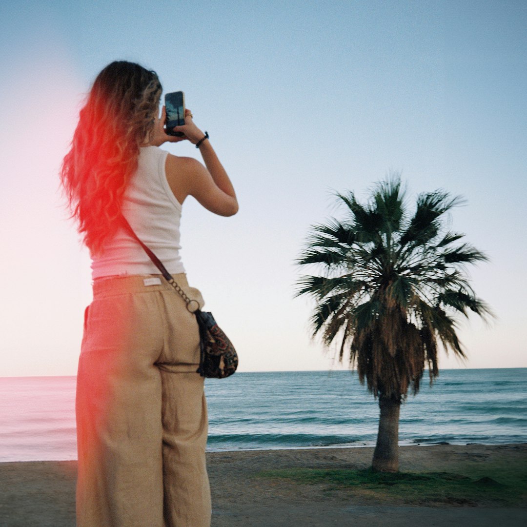 Woman photographing palm tree on málaga beach with light leak