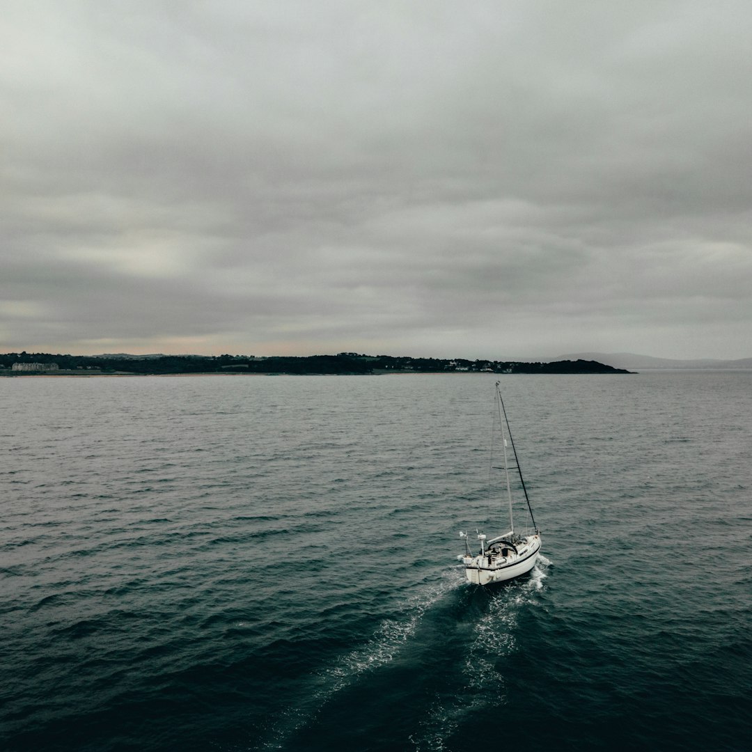 white boat on sea under gray sky during daytime