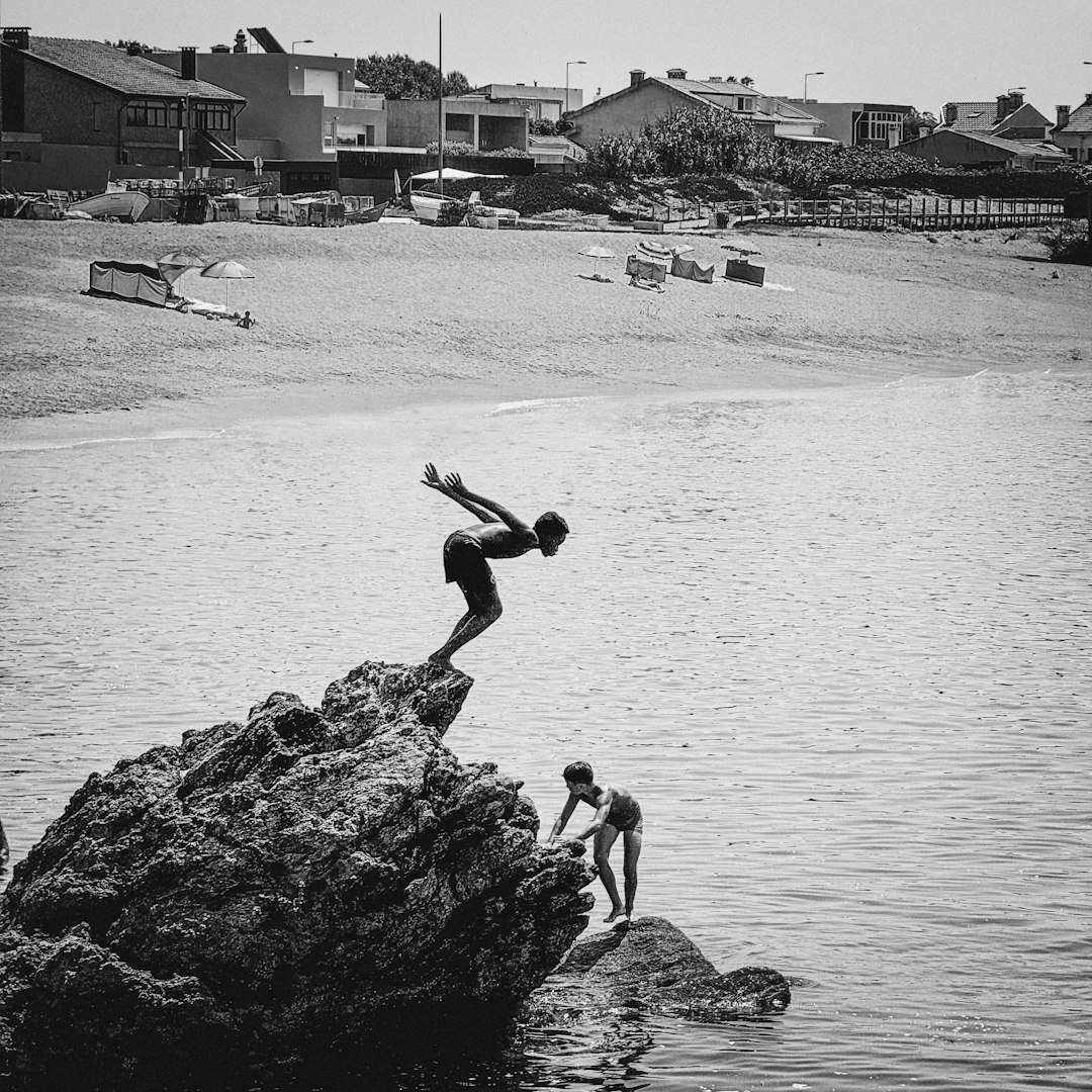Two people jumping off rocks into the water