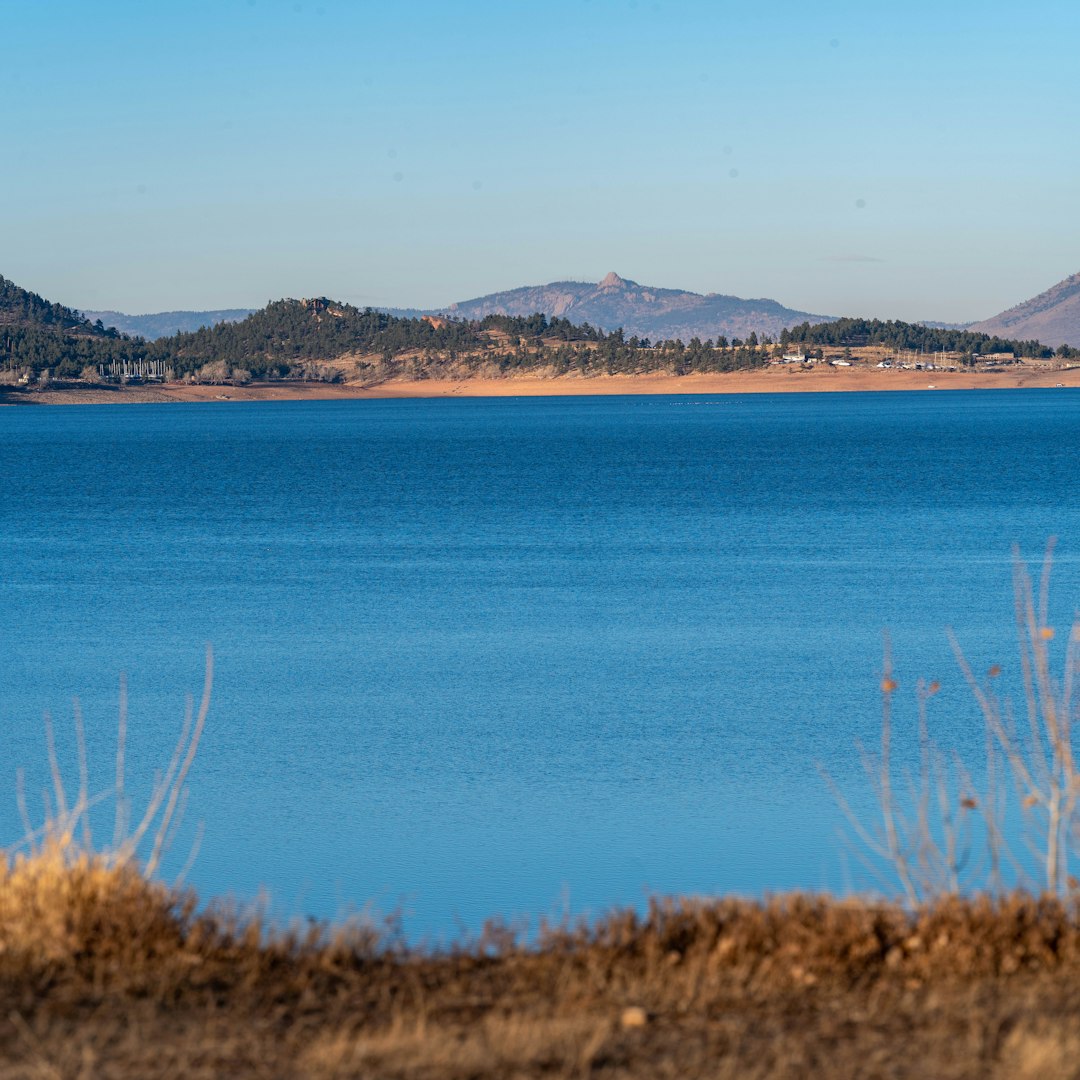 Vast blue lake with distant hills under clear sky