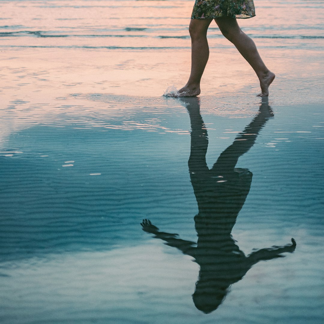 woman walking on body of water beside shore during daytime