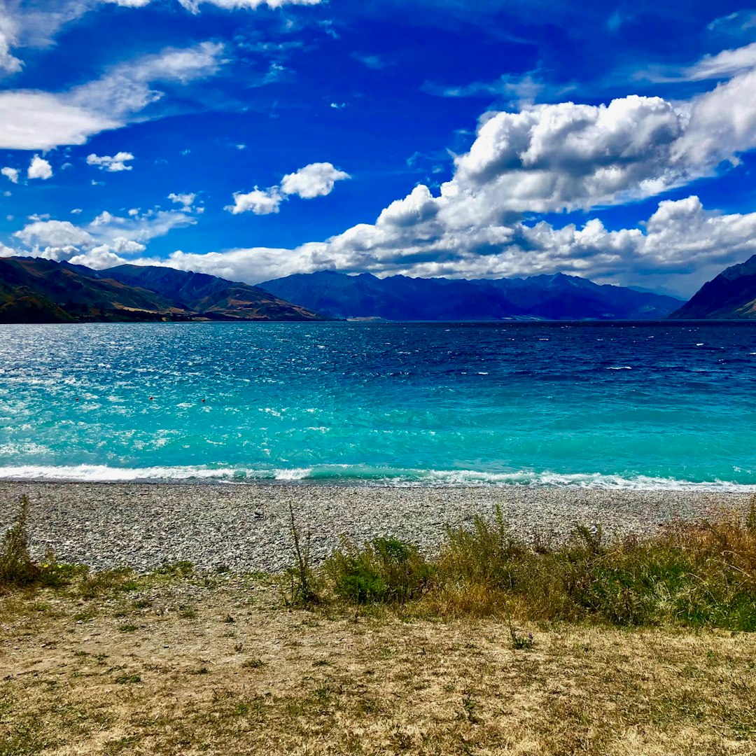 Turquoise lake waters with mountains under a cloudy sky