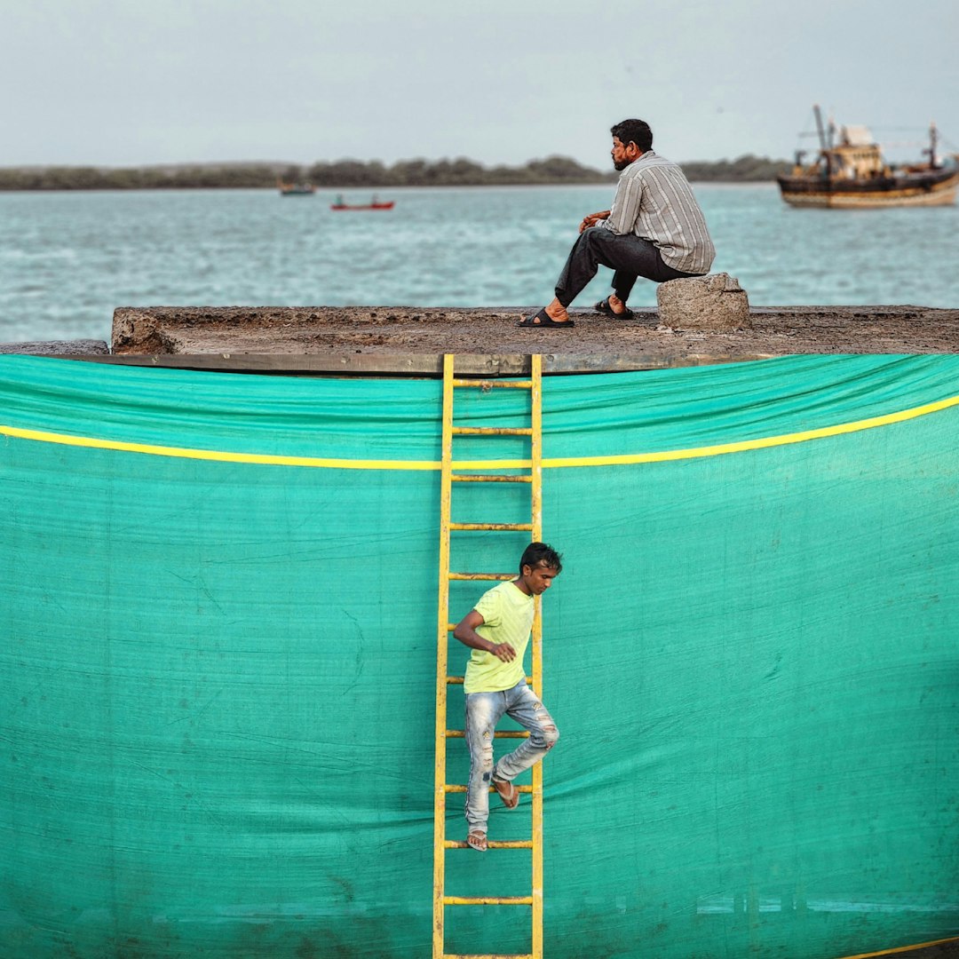 a man standing on a ladder next to a boy on a boat