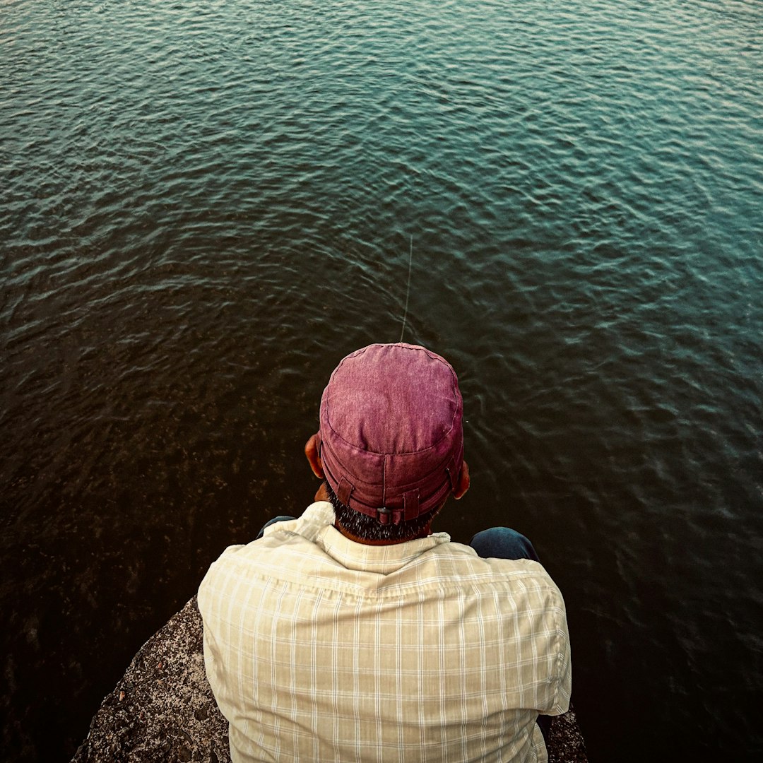 A person in a purple cap fishing in dark water