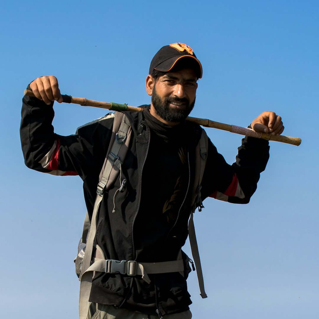 a man holding a stick and wearing a hat
