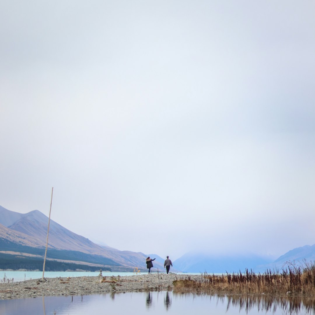 two person standing near body of water