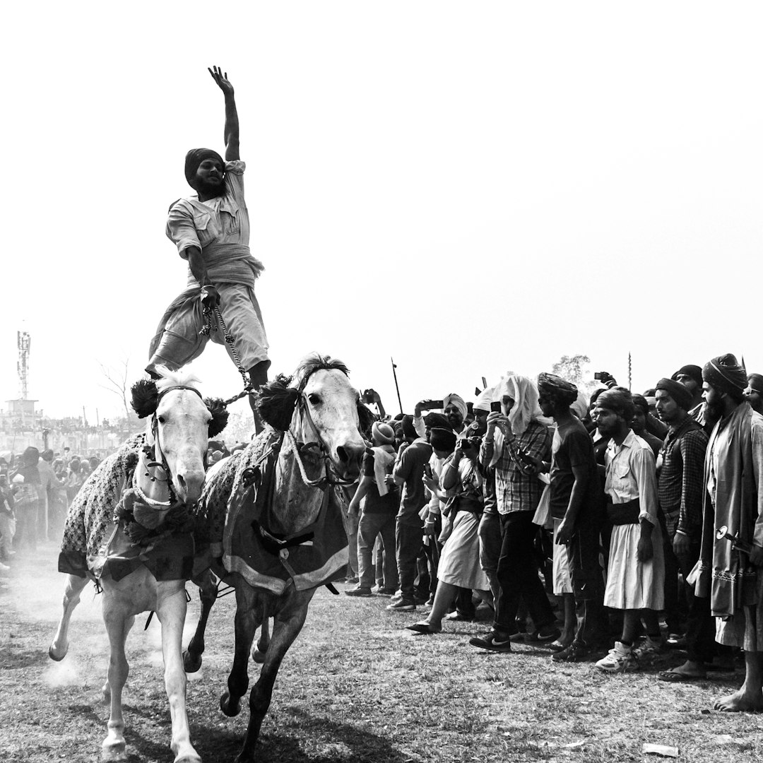 a black and white photo of a man riding a horse