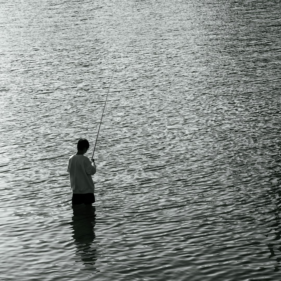 a man standing in a body of water holding a fishing pole