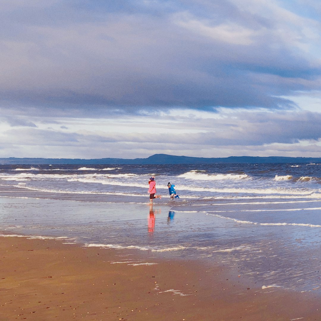 person in red shirt standing on beach during daytime